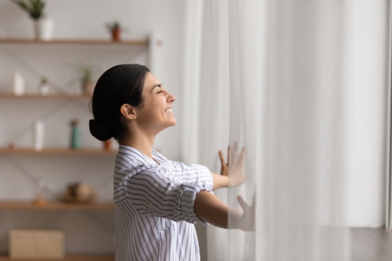 Is It Worth Installing a Ductless Air Conditioner? Standing in a window enjoying sunny weather.